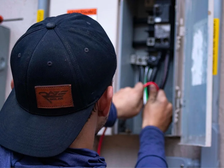An electrician working inside an open residential electrical panel